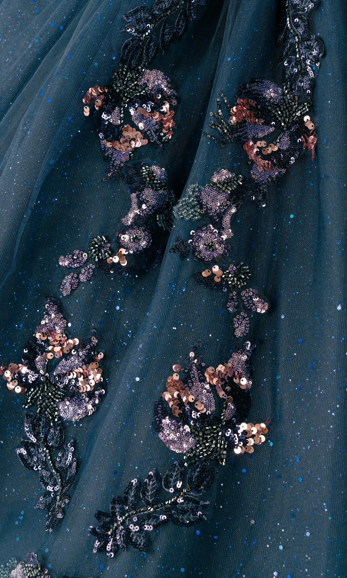 Close-up of the Quinceanera Dress 8440JQ by Cinderella Couture in dark teal with glitter, detailed with intricate floral embroidery and sequins in pink, purple, and gold tones.